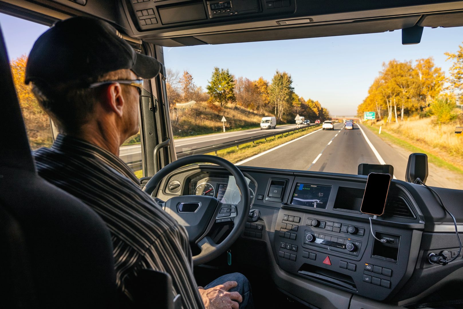 View from inside the cab of the truck. The truck is driving down the road. Car transport. A truck driver drives a truck.
