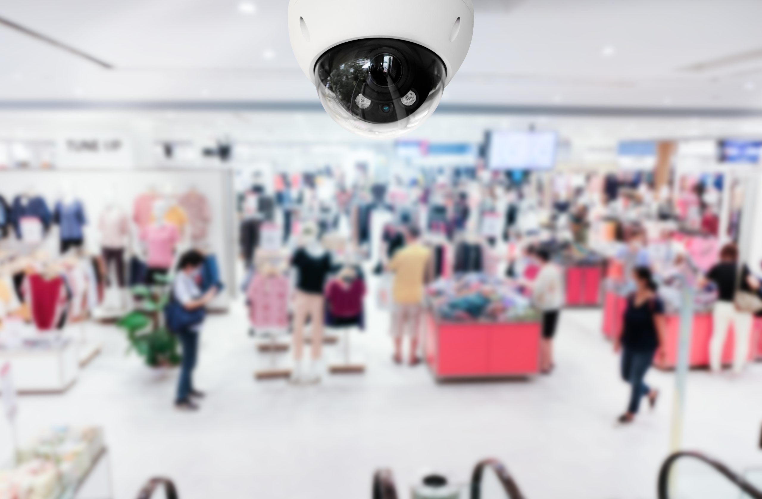 Modern public CCTV camera with blur interior shopping mall background. Recording cameras for monitoring all day and night. Concept of surveillance and monitoring with copy space.