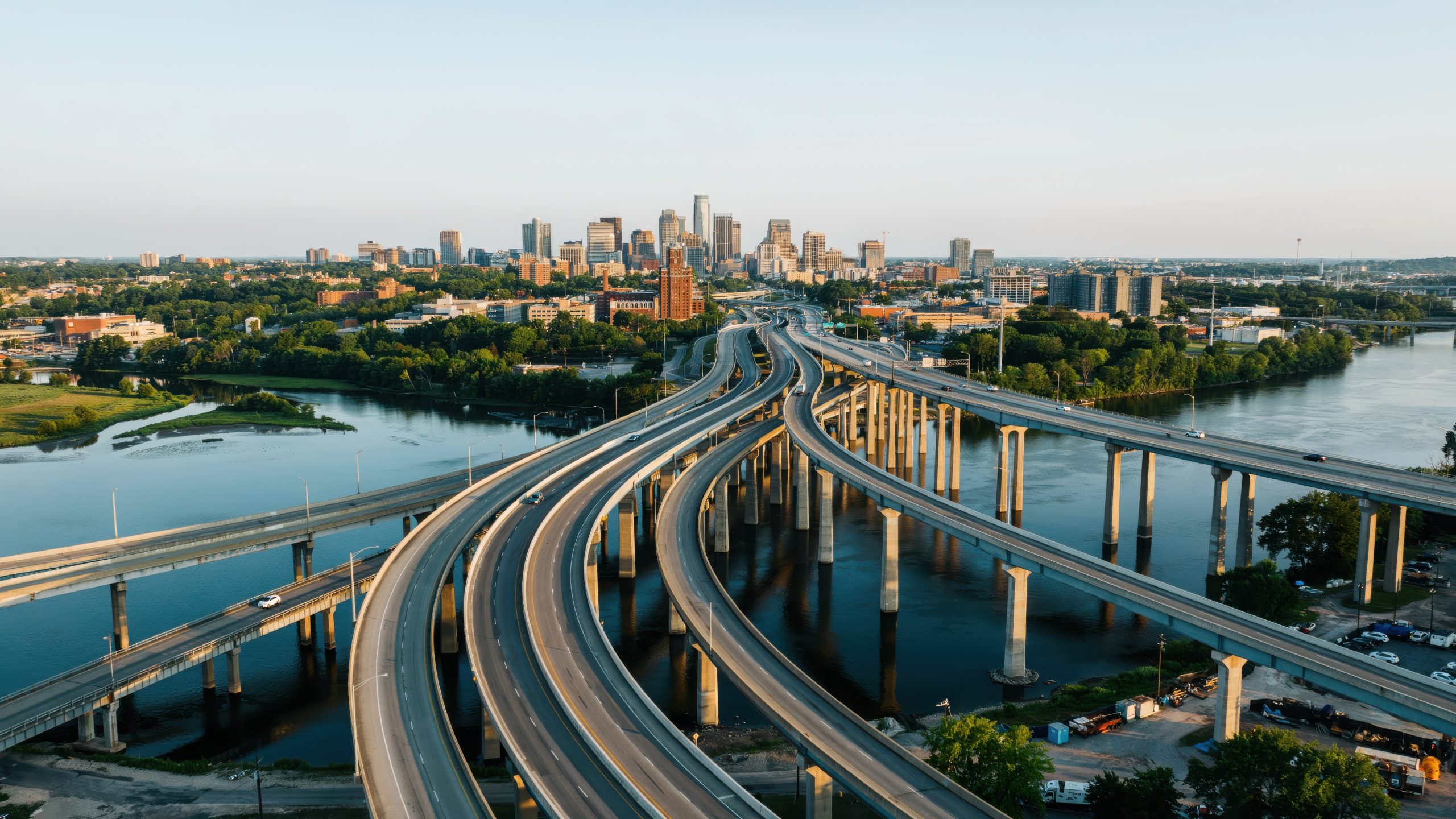 Aerial view of complex highway interchange over water and cityscape.